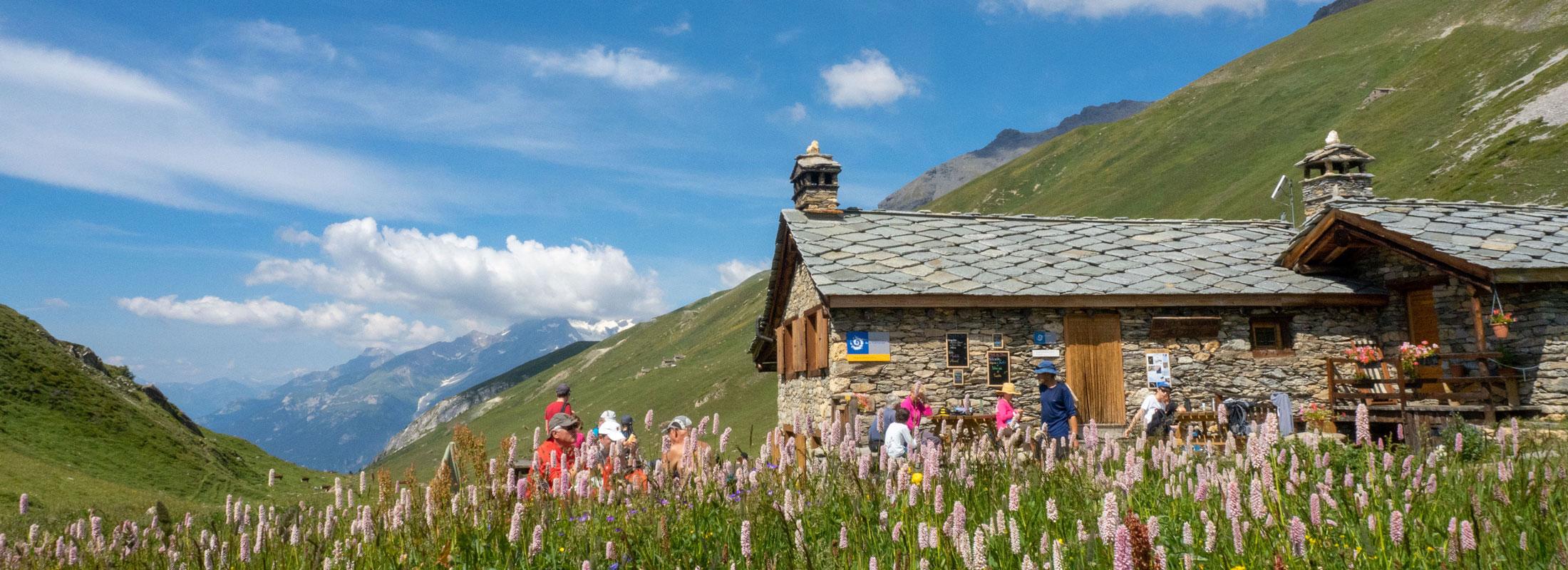 Le refuge PNV de Vallonbrun et sa terrasse occupée par les randonneurs au moment du déjeuner. Lanslevillard, commune de Val Cenis.